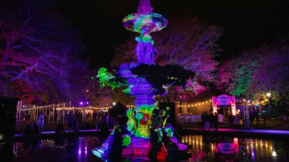 Darkly lit fountain with colourful projection art