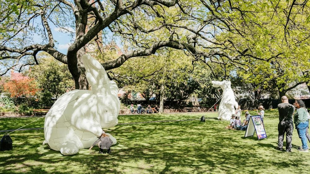 Green foliage in daylight, large while rabbit installations inside the Festival Hub