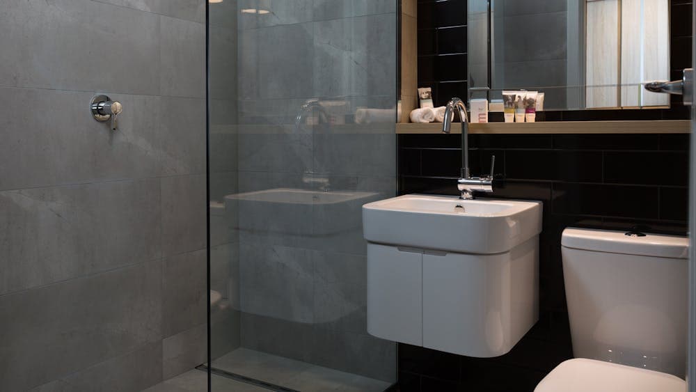Modern bathroom, showing shower, toilet, hand basin and mirror.