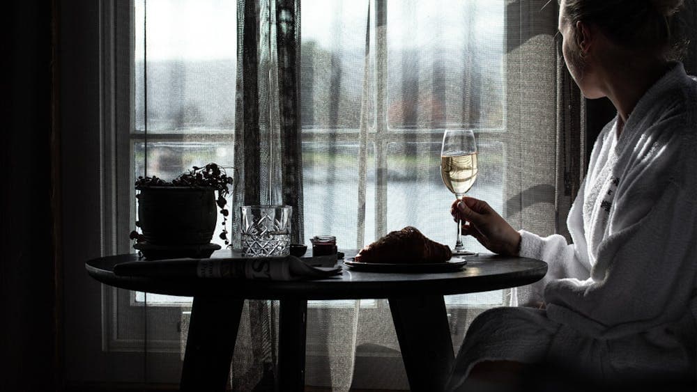 A person sitting a table looking out the window at the water
