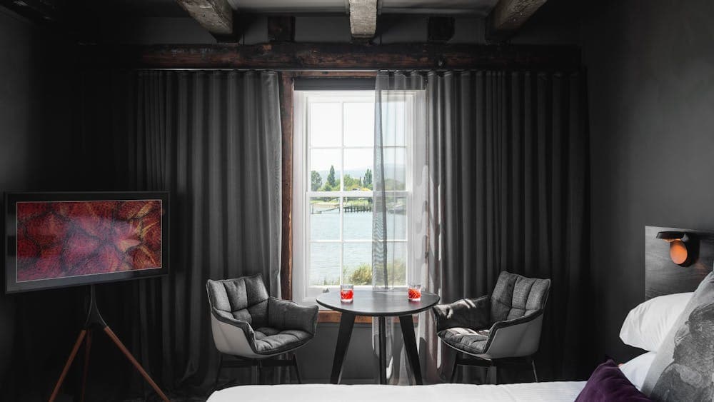 A king bed with a stylish table and chair by the window