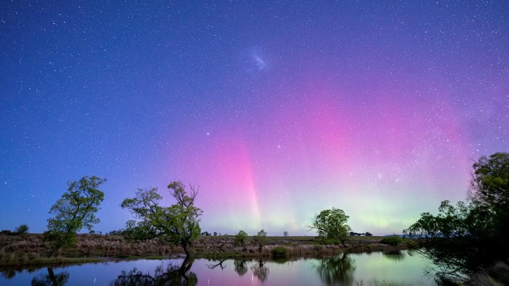 Stunning pink, purple and green glow of the Aurora Australis reflecting in the South Esk River.