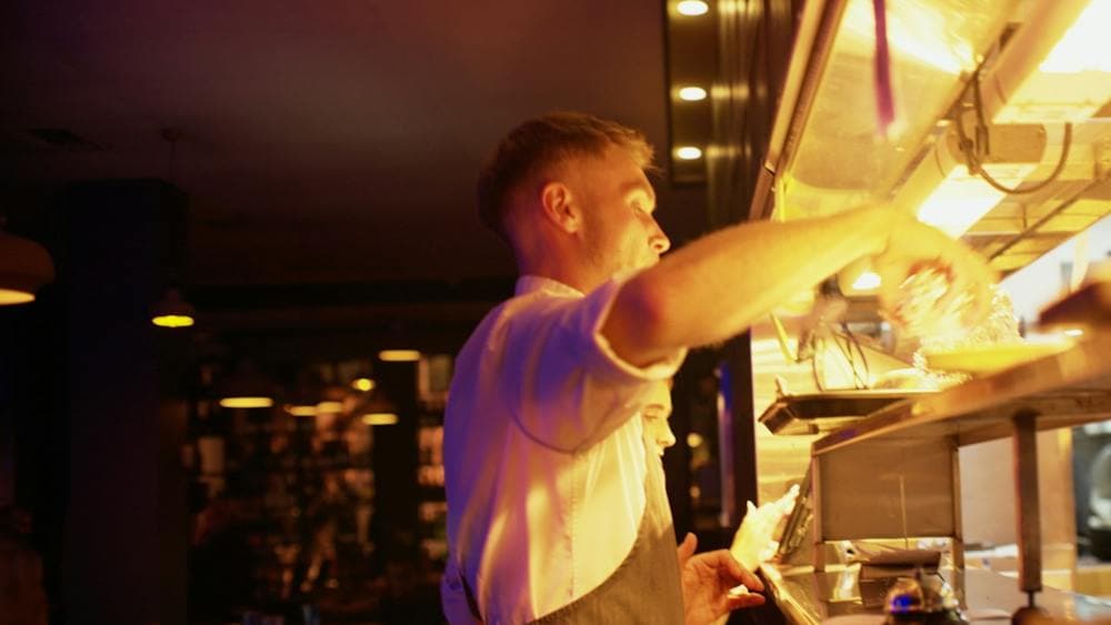 Waiter collecting dishes from the kitchen pass at Mudbar Restaurant in Launceston